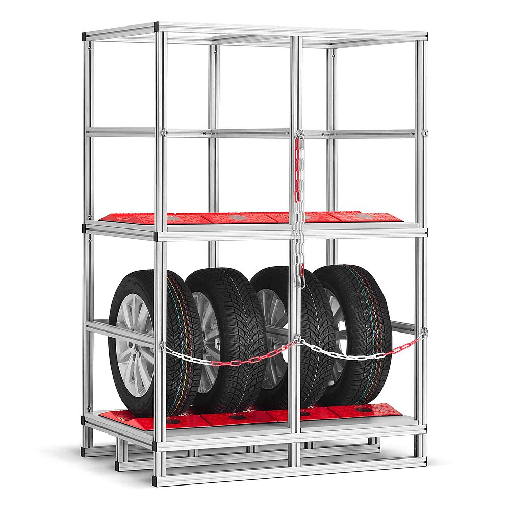 a tyre rack made of aluminium profiles with two storeys, each lined with red TyreGuard® tyre protectors, the lower storey loaded with four tyres on alloy rims and secured with a cross-wise chain, isolated on white background