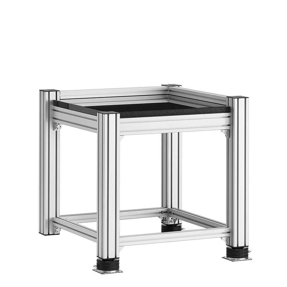 a square, cube-shaped metrology table made of aluminium profiles, with thick black granite table top, mounted on three black air-cushion vibro-mounts FLN, isolated on white background