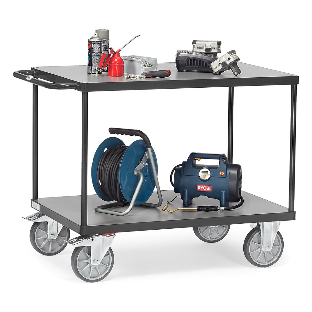 a dark-grey FETRA® table top cart with rear push bar, two light-grey wooden platform shelvings top and bottom, two fixed wheels at the front, two fastenable steering wheels at the rear, and loaded with a cable drum, pump and other work utensils, isolated on white background