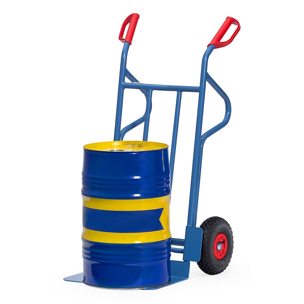a blue FETRA® sack truck made of steel tube with air tyres, supporting skids for horizontal positioning, large loading shovel, red handles, and loaded with a blue-yellow striped oil barrel, isolated on white background