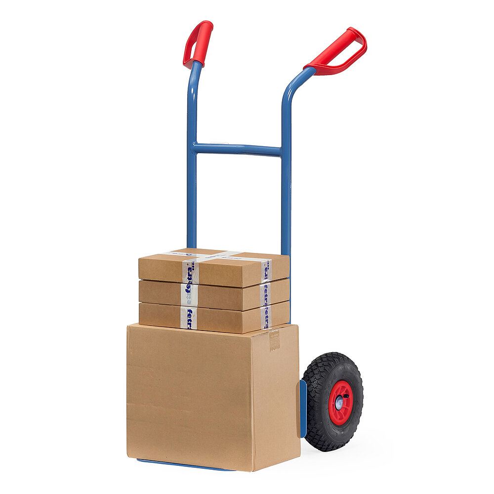 a blue FETRA® stacking truck made of steel tubes with air tyres, red handles and loaded with brown cardboard boxes, isolated on white background