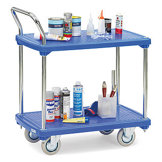 a FETRA® storeroom trolley made of zinc-coated steel tubes, with two platforms of sturdy blue plastics, back-bent push bar, two fixed wheels at the front, two steering wheels at the rear, and loaded with various colour cans and laquering sprays, isolated on white background