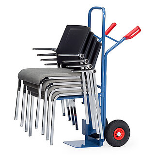 a blue FETRA® chair truck made of steel tubes for the transport of stackable chairs, with black air tyres, loading shovel, fixed chair-carrying device consisting of two horizontal round hollow bars, red handles, and loaded with a stack of four steel tube chairs, isolated on white background