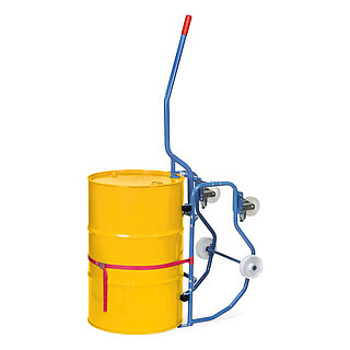 a blue FETRA® drum trolley made of steel tube with two fixed wheels and two fastenable steering wheels made of white polyamide, standing upright, loaded with a yellow 200 litre metal barrel secured with a red lashing strap, and with an additional stick-on lever at the top to facilitate the tipping process, isolated on white background